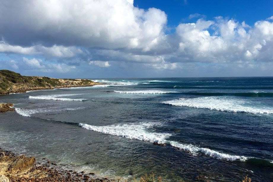 margaret river beach with fluffy clouds above the waves rolling in