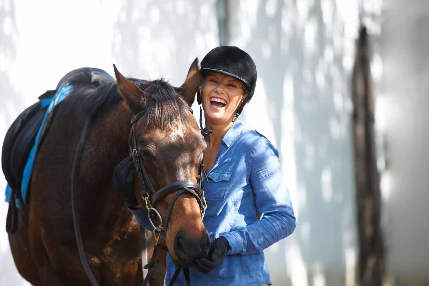 horse rider standing next to horse and laughing in margaret river