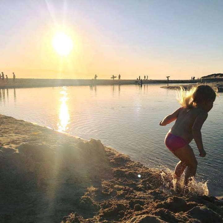 young girl frolics at the margaret river mouth at sunset