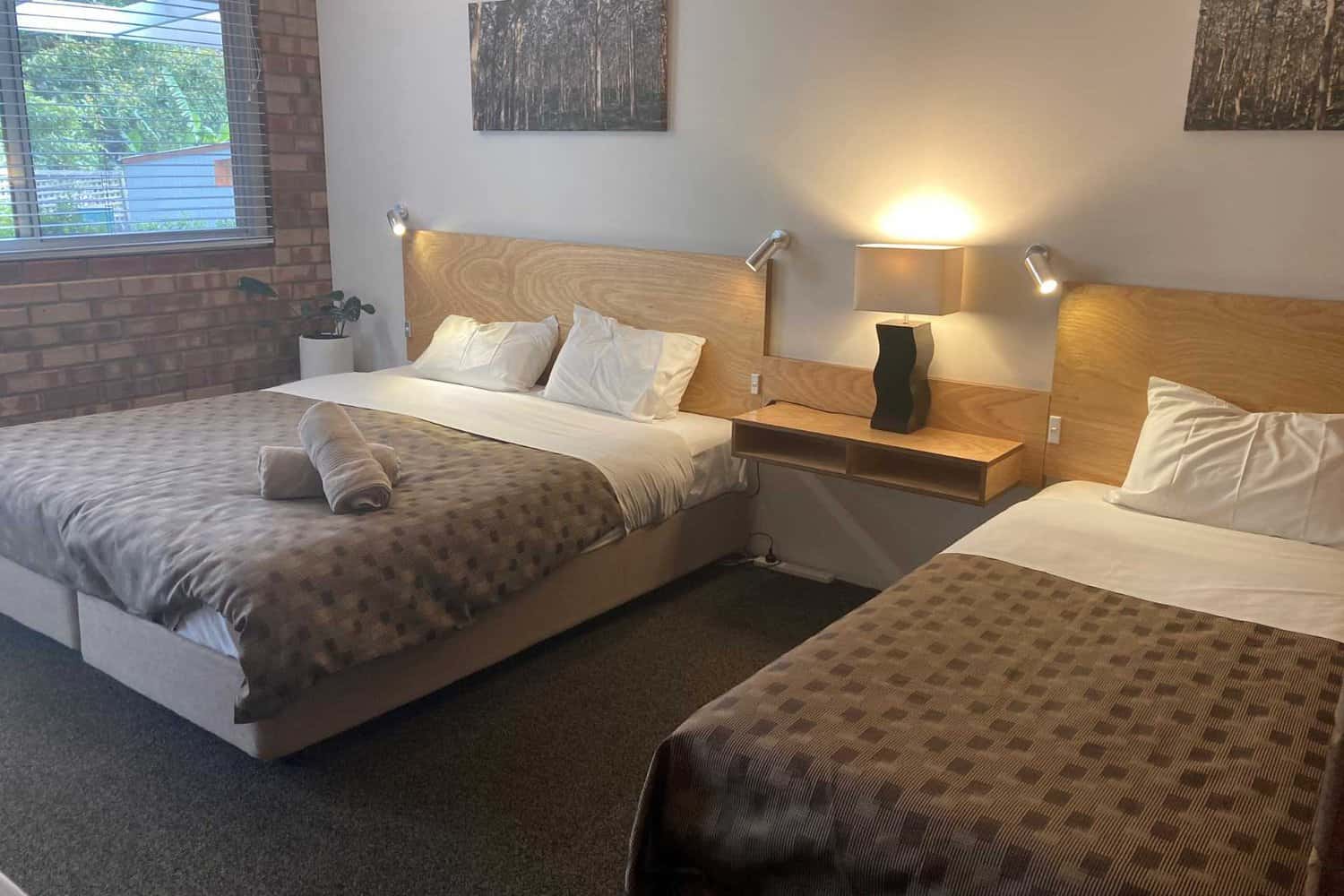 Two large beds in a stylishly decorated room at Edge of the Forest Motel, complete with neatly folded towels on the bed.