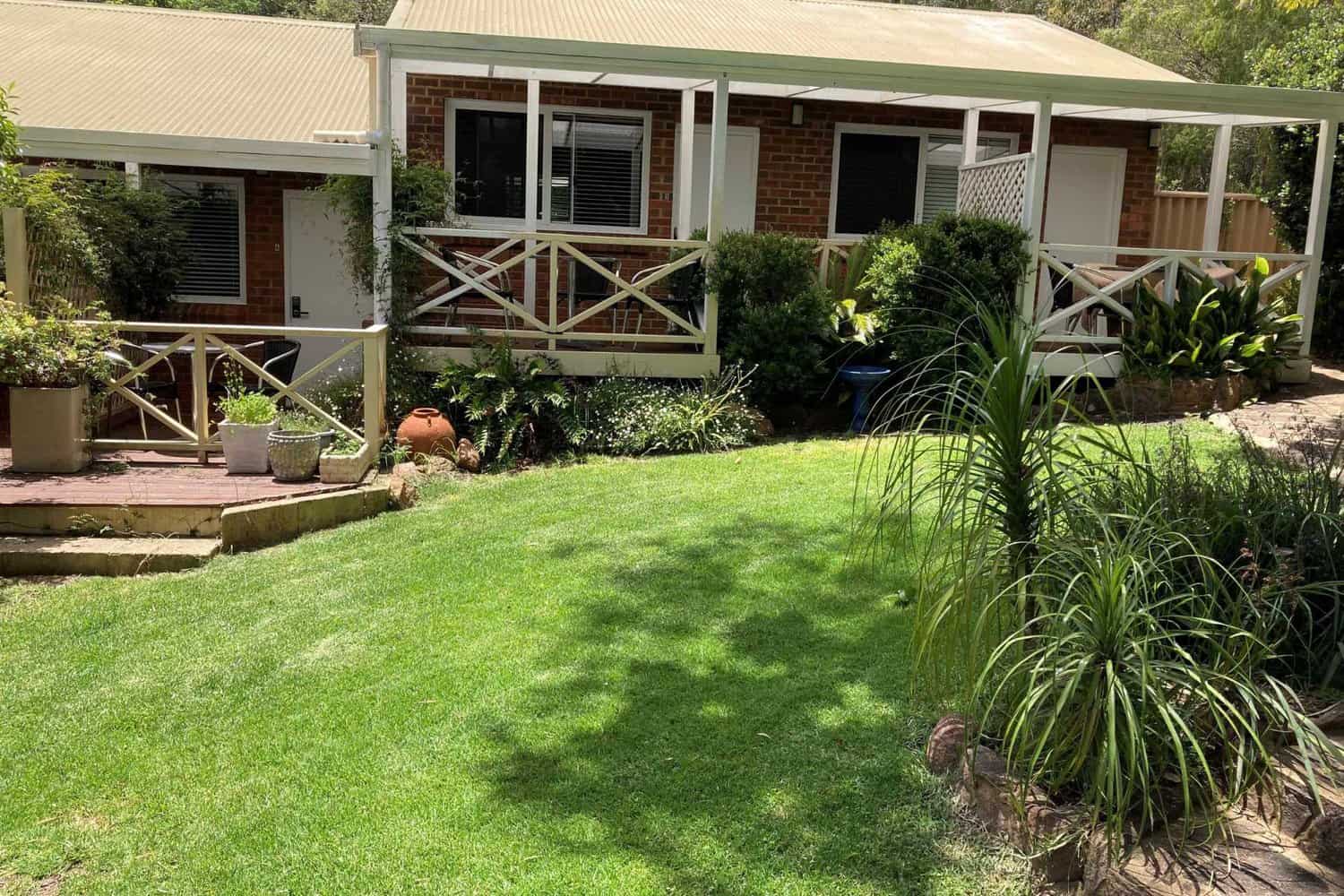 Shaded lawned area at Edge of the Forest Motel, with cozy rooms visible in the background.