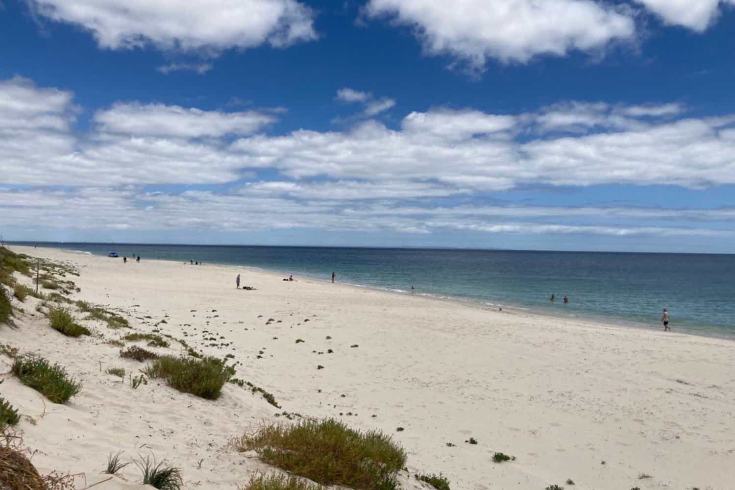 Overcast summer view of Peppermint Grove Beach, with calm grey skies meeting the serene waters, and the sandy shore gently curving into the distance, one of the popular Margaret River beaches on offer.