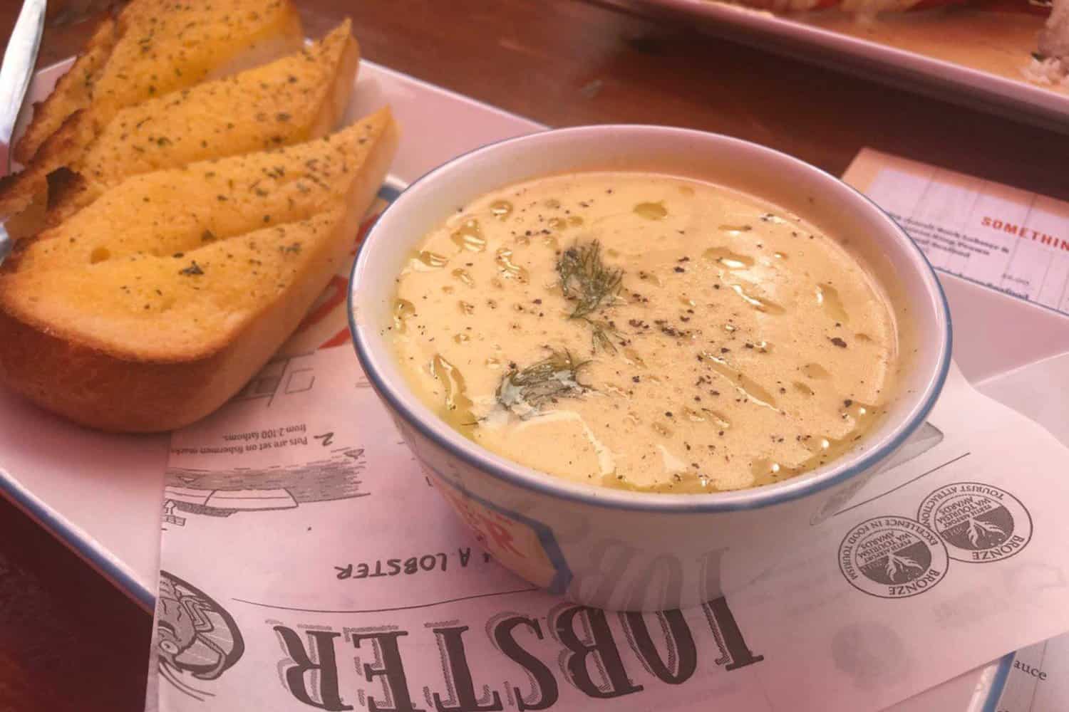 Mouthwatering clam chowder served in a bowl, accompanied by a side of garlic bread at the Lobster Shack, a popular stop on the Perth to Exmouth road trip, offering a taste of local cuisine
