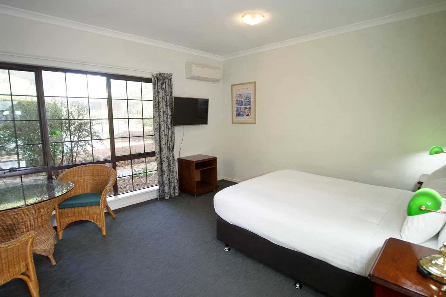 Complete hotel experience featuring a cozy queen size bed, functional table and chairs, modern TV, and convenient air conditioning for ultimate guest comfort.