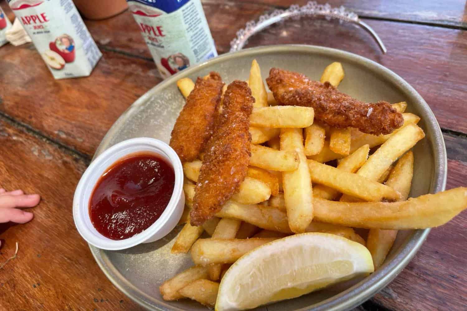 A delicious serve of kids fish and chips served at a Margaret River brewery, with crispy crumb and golden fries. The dish is garnished with fresh lemon and served with a side of tomato sauce.
