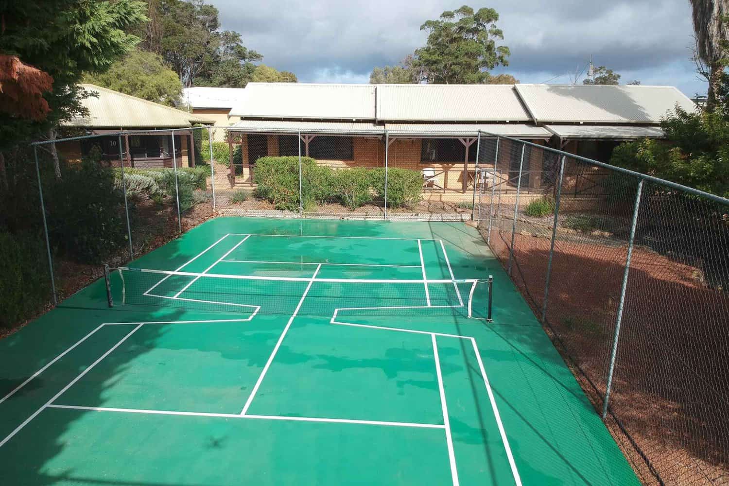 A private tennis court surrounded by lush greenery, perfect for a leisurely vacation in Western Australia.