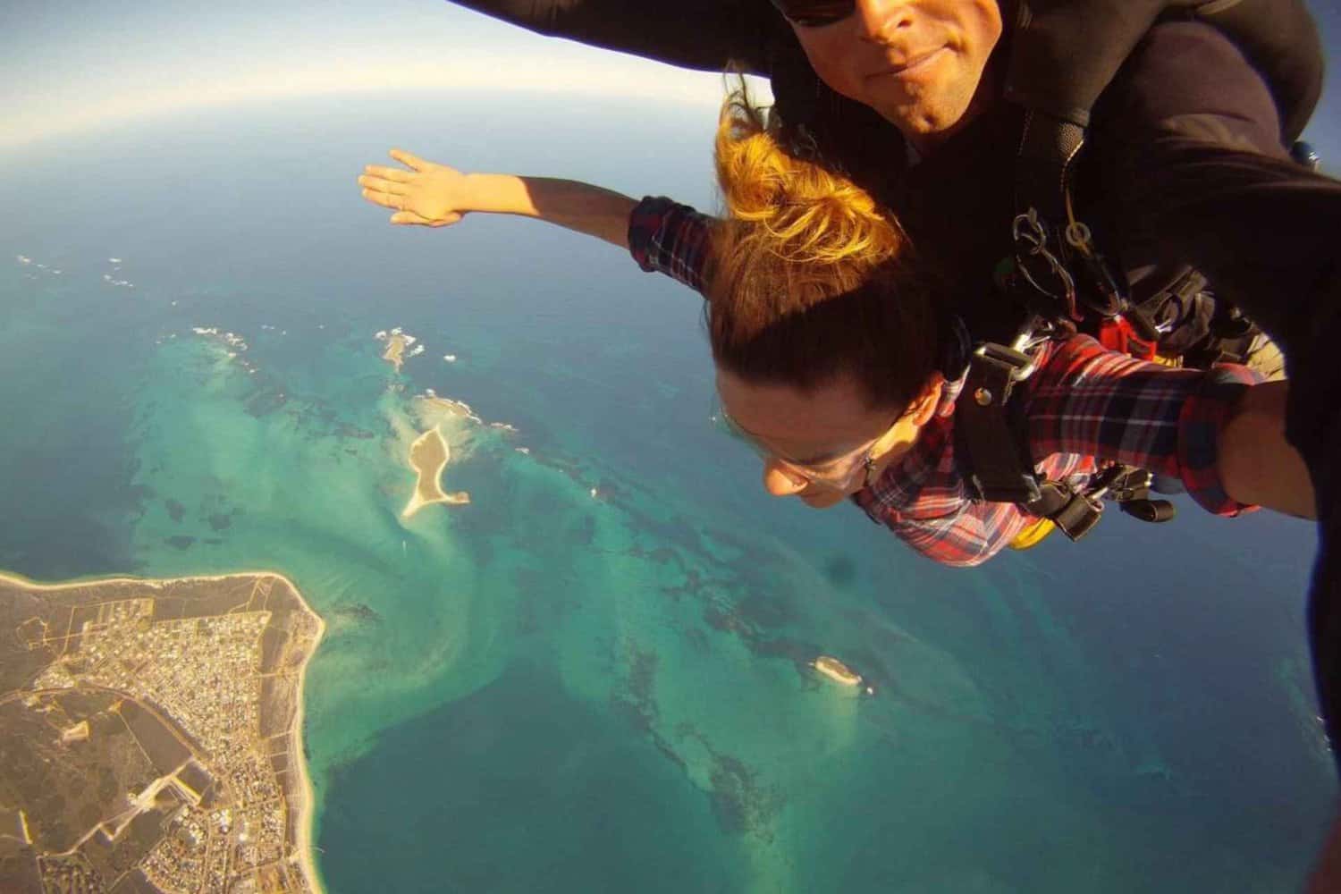 Exhilarating skydiving experience over Jurien Bay during the Perth to Exmouth adventure, featuring the jumper (me!) looking down at the stunning ocean below, while the instructor captures a thrilling selfie of the tandem dive