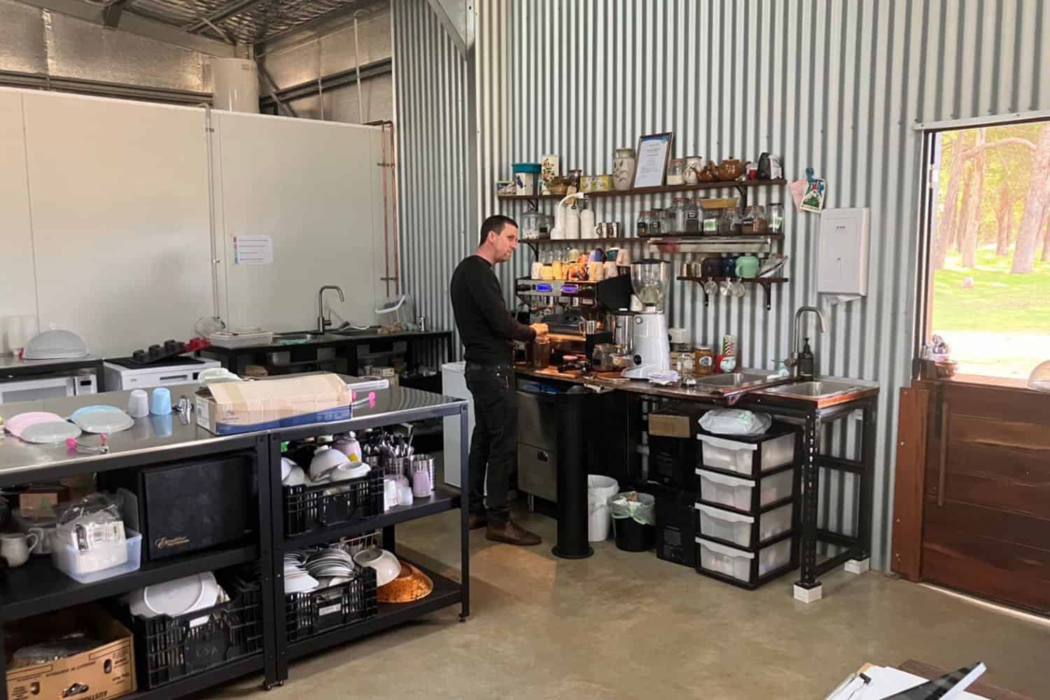 A skilled barista preparing the best coffee in Margaret River. The image shows a man behind the counter of a cafe, operating a coffee machine with expertise and precision. The aroma of freshly brewed coffee fills the air as the barista creates a perfect cup of java for delighted customers