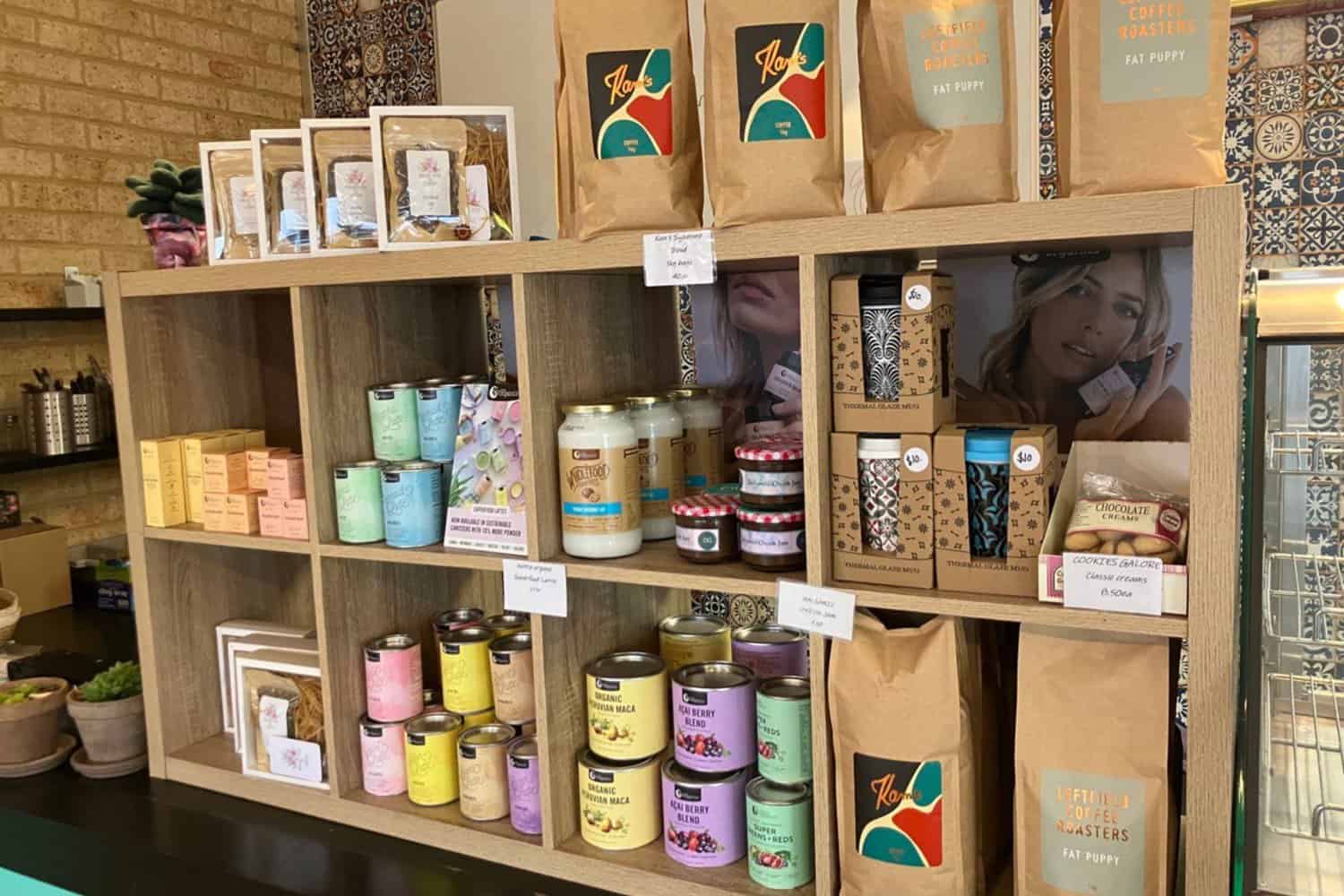 An enticing display of coffee beans and related items at a cafe in Margaret River. The image showcases a shelf adorned with various coffee bean packages, grinders, and brewing equipment, inviting visitors to explore the world of coffee. The assortment of beans promises the best coffee in Margaret River, with each package showcasing its unique flavors and origins