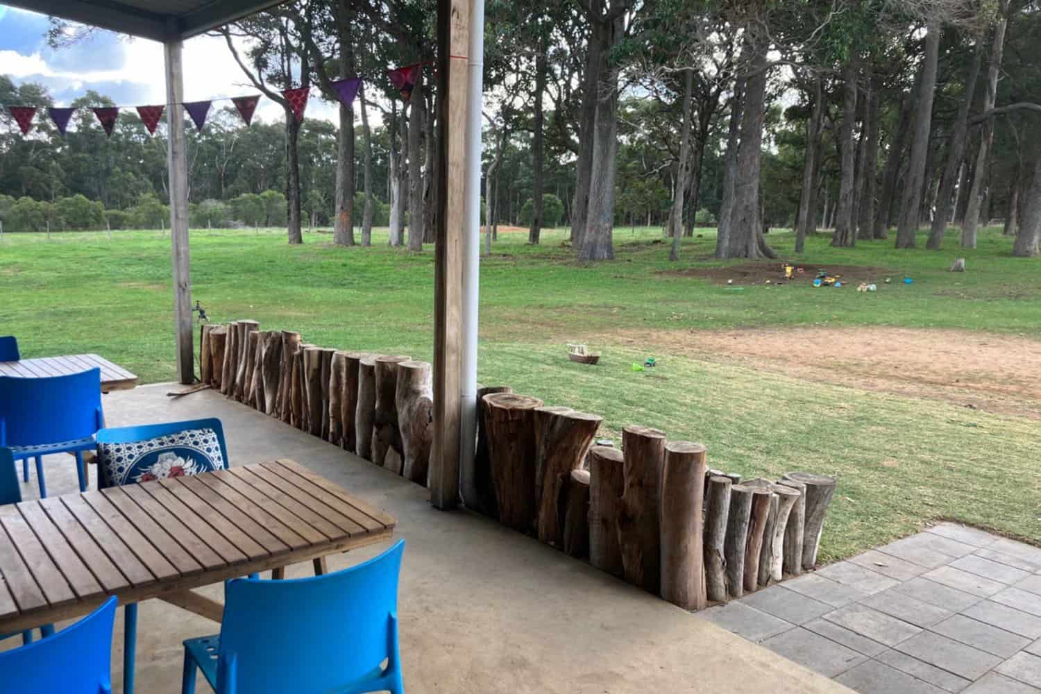 Scenic coffee tables overlooking a spacious grass lawn in Margaret River. The image showcases a peaceful outdoor setting where customers can enjoy the best coffee in the area. Children's toys are scattered on the lawn, creating a family-friendly atmosphere for visitors.
