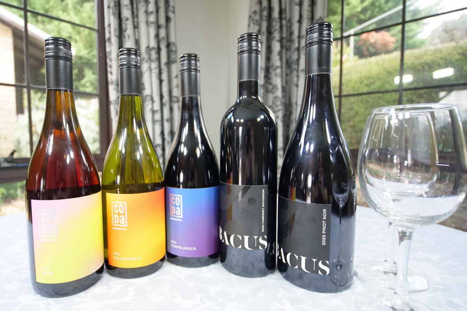 A glass of a local Margaret River wine sits next to a range of wine bottles on the table in a hotel room, emphasizing the difference between staying at a hotel and eating at a restaurant. 