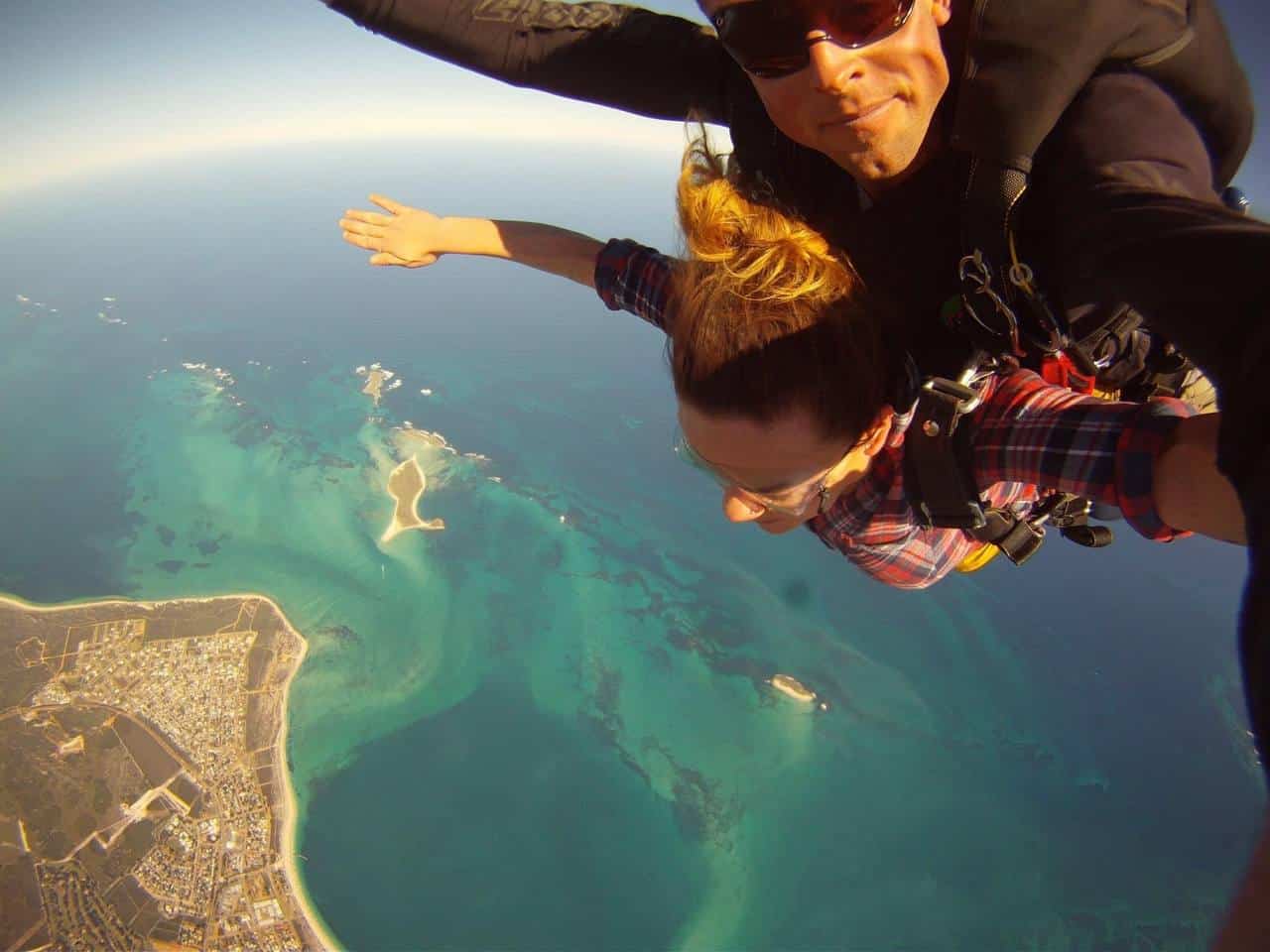Thrilling first-person perspective of a skydiving adventure over the stunning turquoise waters of the Indian Ocean, at Jurien Bay near Perth, with coastal town views below, on a clear day making for an unforgettable experience.