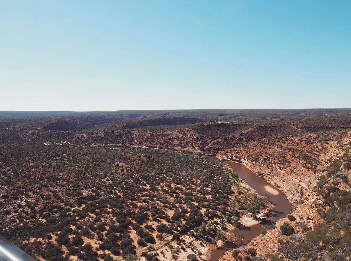 Panoramic view of a winding river flowing through the arid gorges of Kalbarri National Park, showcasing the unique landscape along the travel route from Perth to Kalbarri in Western Australia.