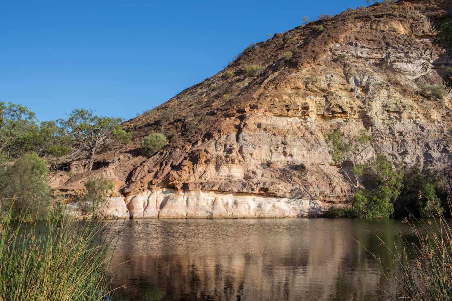 Ellendale Pool, a natural waterhole surrounded by steep rocky cliffs and lush vegetation, located near Geraldton. A serene oasis that is a favorite for free camping enthusiasts seeking the beauty of Western Australia's natural landscapes.